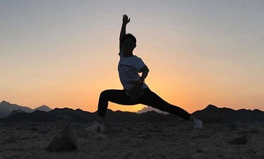 Dynamic silhouette of a person practicing yoga against the Giza Pyramids during sunset, showcasing Egypt tours and desert exploration. Perfect for adventure seekers eager to experience Egypt's iconic landmarks.