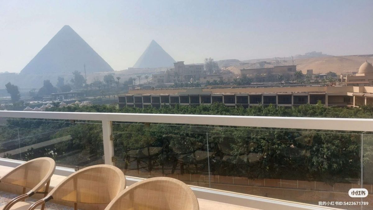 Panoramic view of the Giza Pyramids from a modern balcony overlooking the desert in Cairo, Egypt
